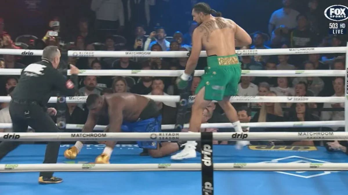 Boxer in green celebrating as opponent kneels down