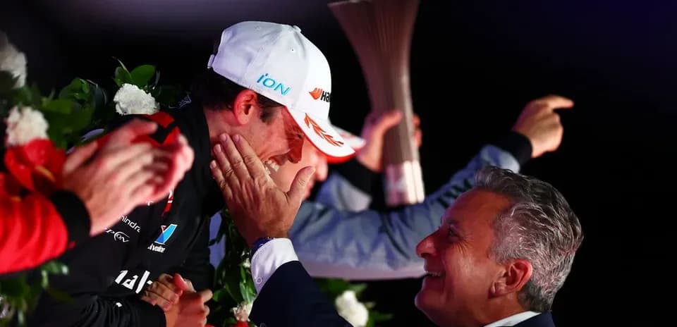 Driver celebrating with team member on podium