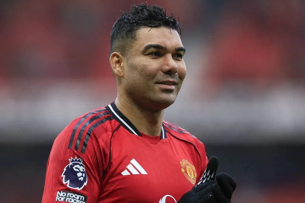 Futbolchi qizil formada, maydonda tabassum qilmoqda