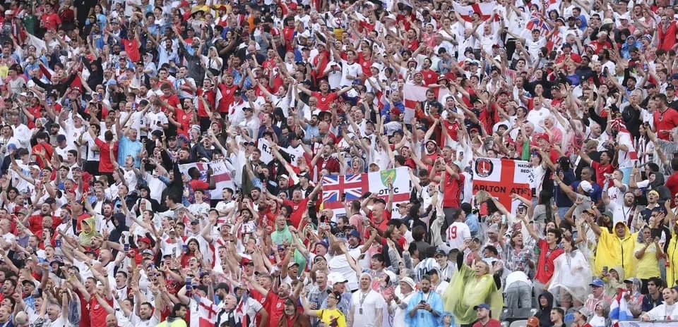 Football fans cheering in stadium wearing team colors