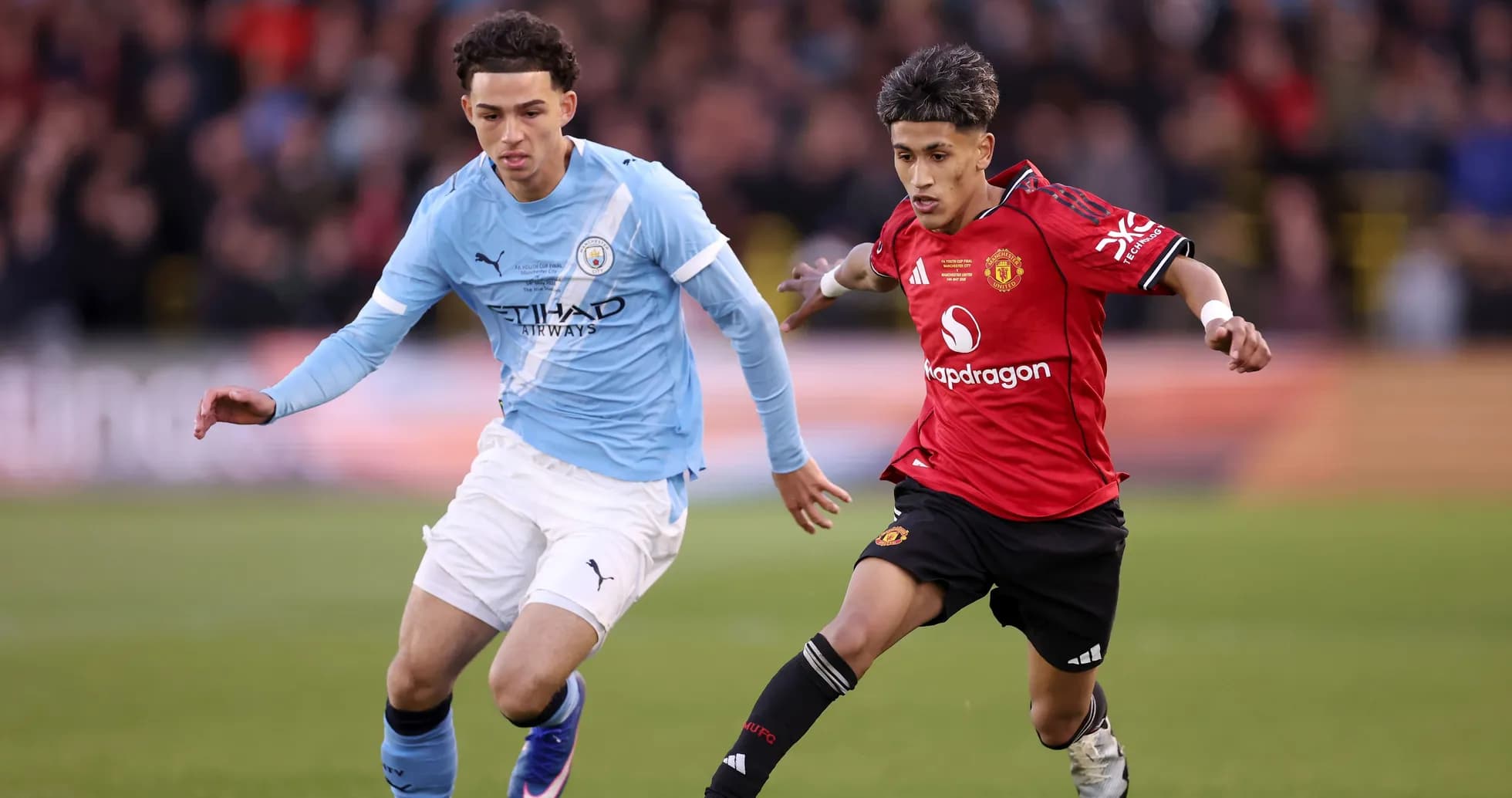 Manchester City and Manchester United players competing for ball
