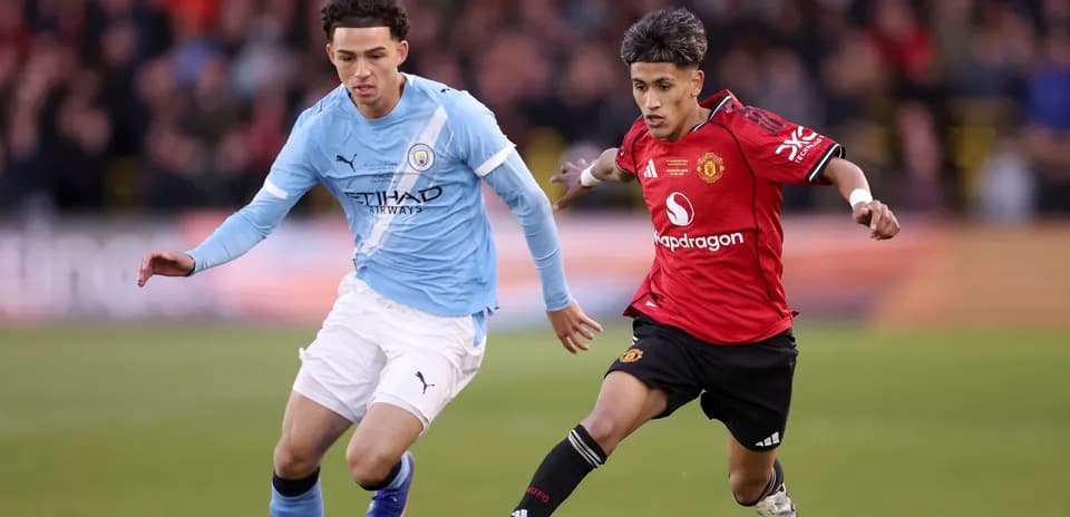 Manchester City and Manchester United players competing for ball