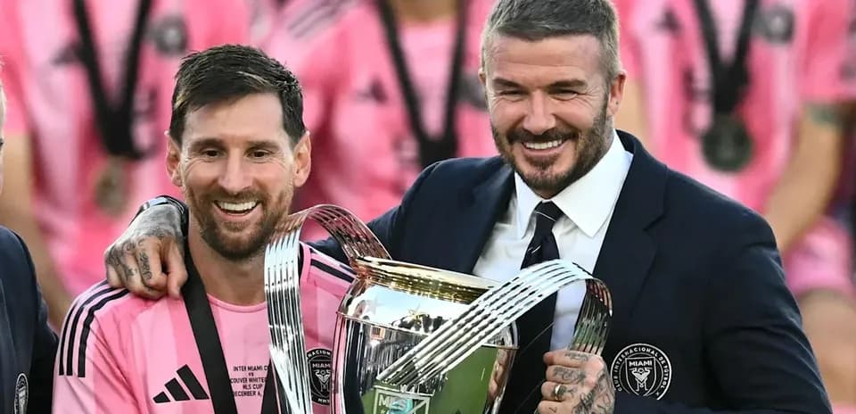 Messi and Beckham holding trophy after match