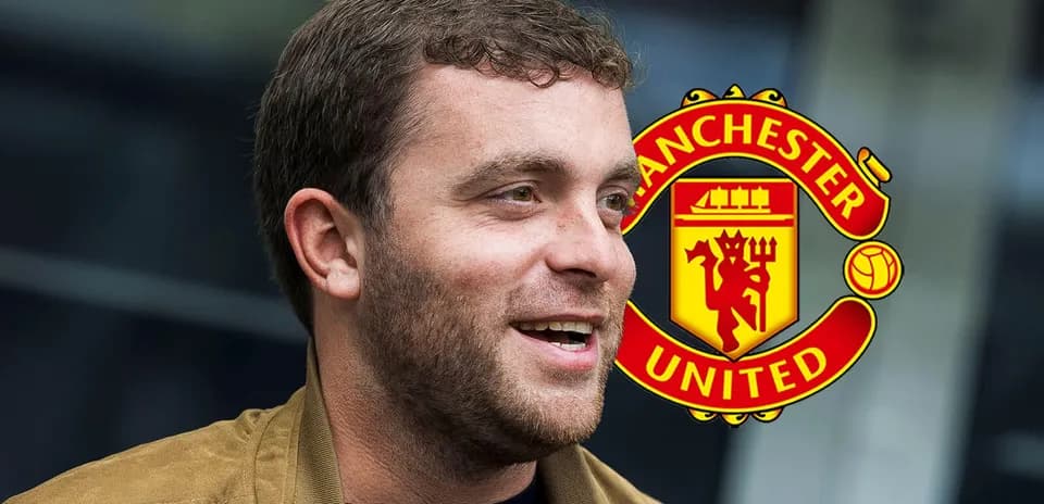 Shirted man smiling with Manchester United logo behind