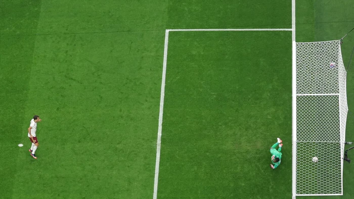 Player approaching goal while goalkeeper prepares to save Player approaching goal while goalkeeper prepares to save