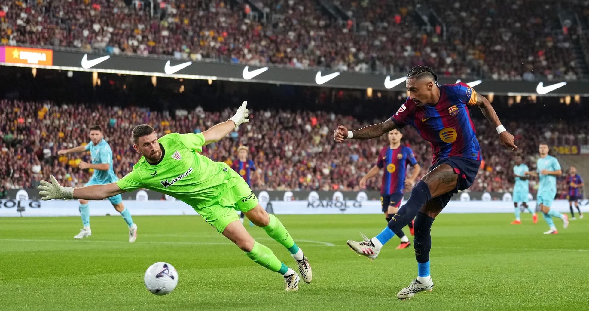 Barcelona player shooting while goalkeeper attempts to save Barcelona player shooting while goalkeeper attempts to save