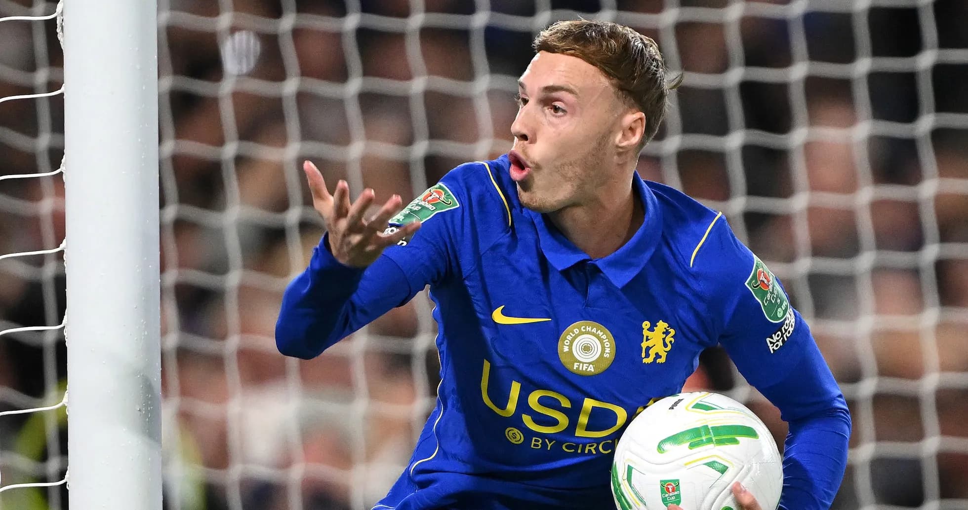 Futbolchi darvozaga to'pni ko'tarib gest qilmoqda Futbolchi darvozaga to'pni ko'tarib gest qilmoqda