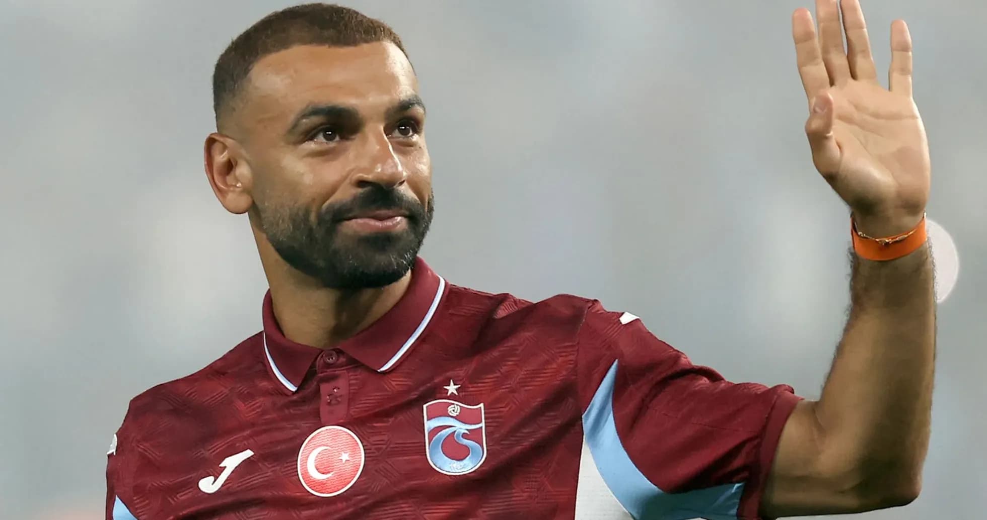 Futbolchi qo'lini ko'tarib salom bermoqda Futbolchi qo'lini ko'tarib salom bermoqda