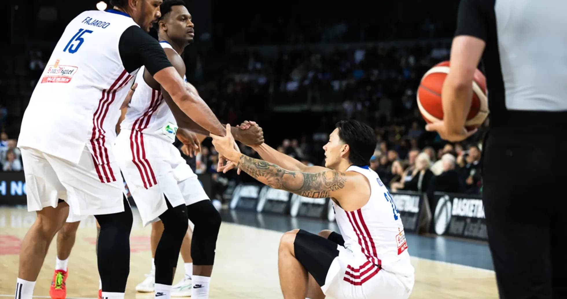 Two players assisting teammate getting up during game Two players assisting teammate getting up during game