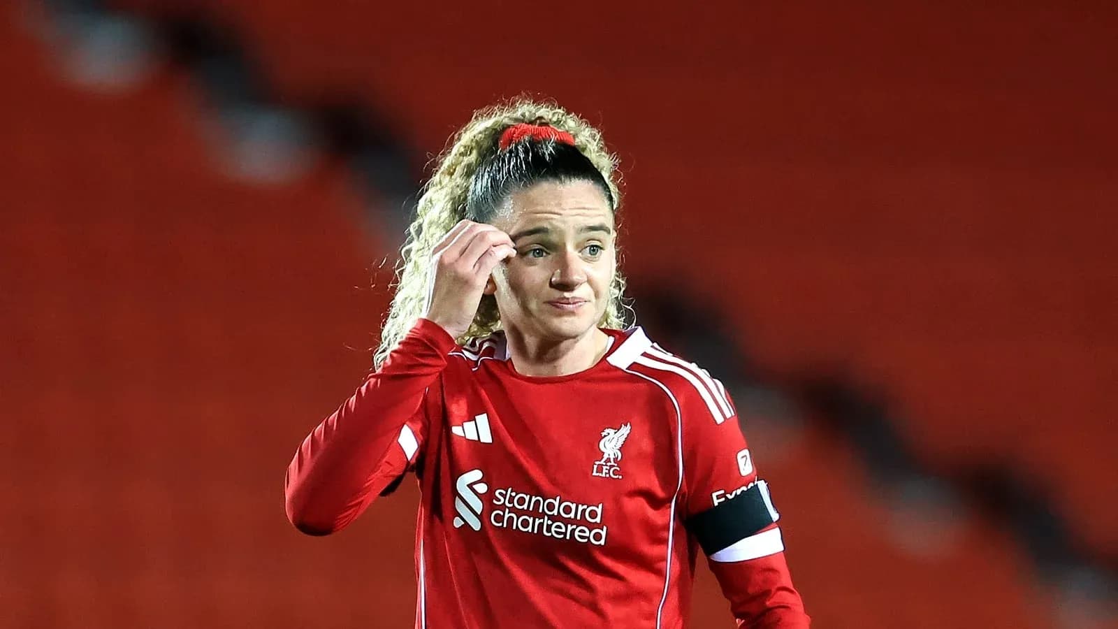 Futbolchi LFC formasida, maydonda turgan ayol Futbolchi LFC formasida, maydonda turgan ayol