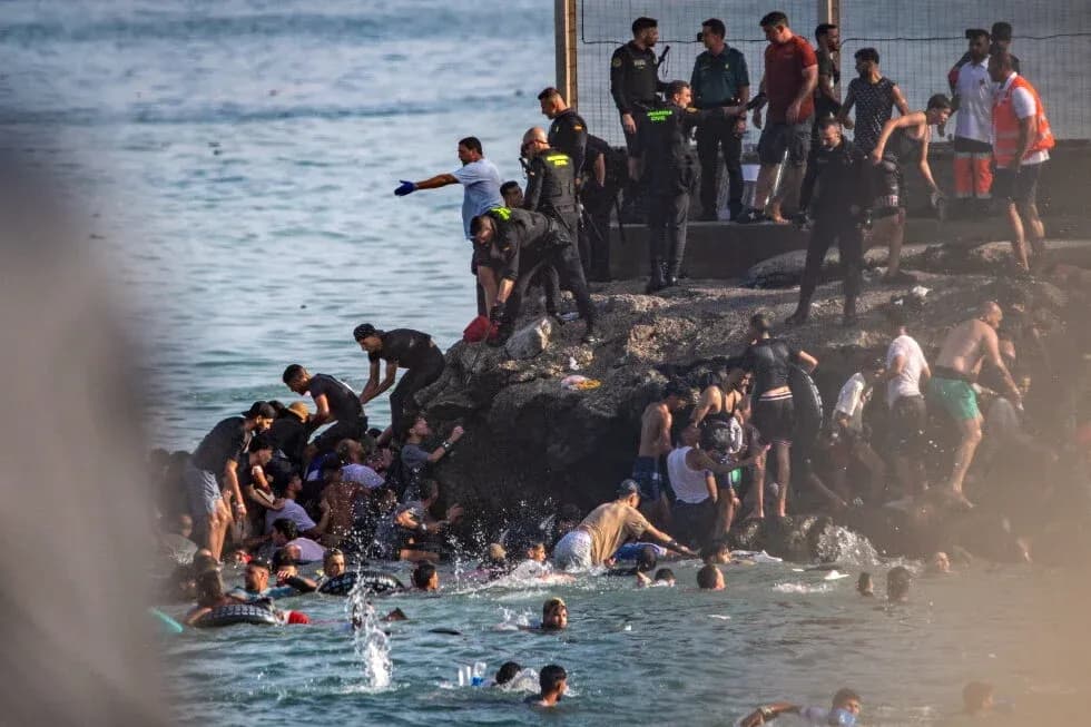 Many people in water and on rocks near shore Many people in water and on rocks near shore