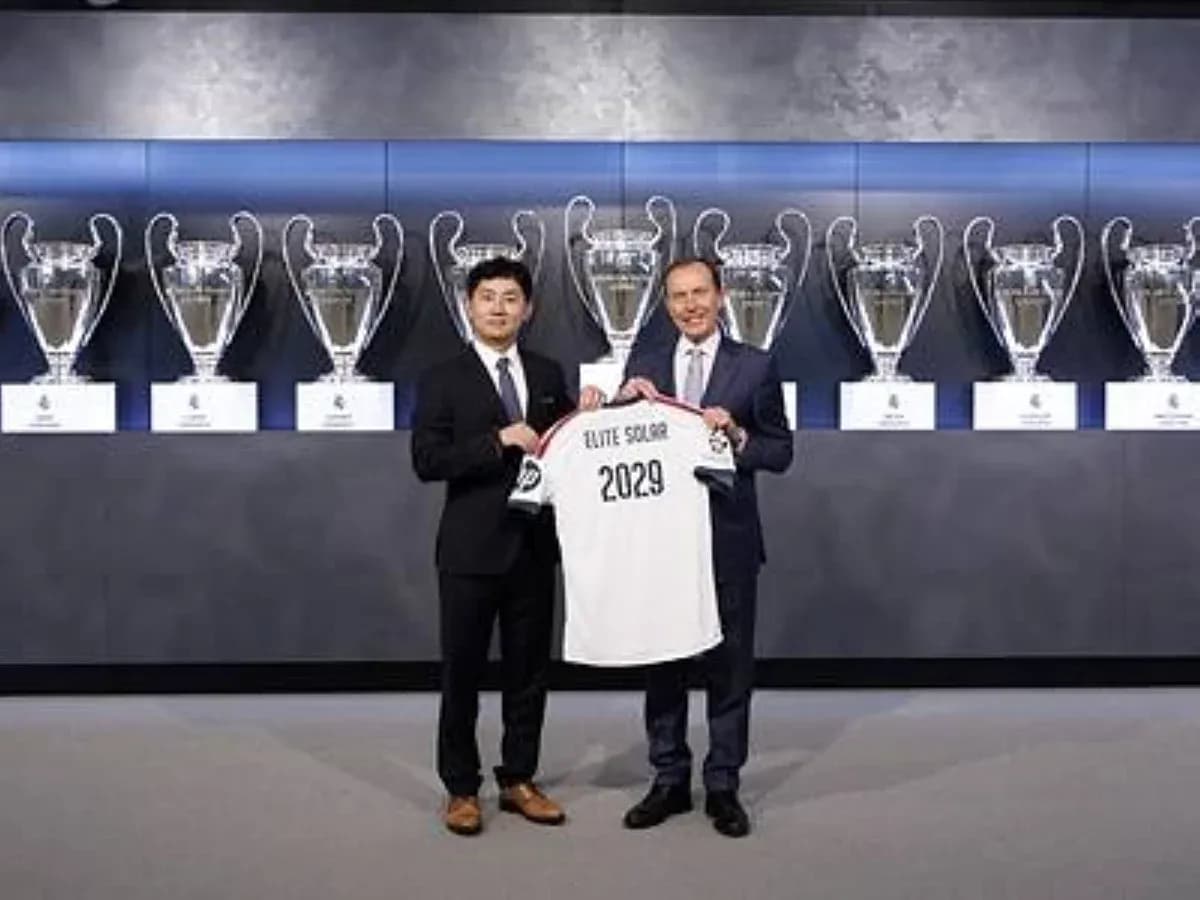 Two men holding a jersey in front of trophies Two men holding a jersey in front of trophies