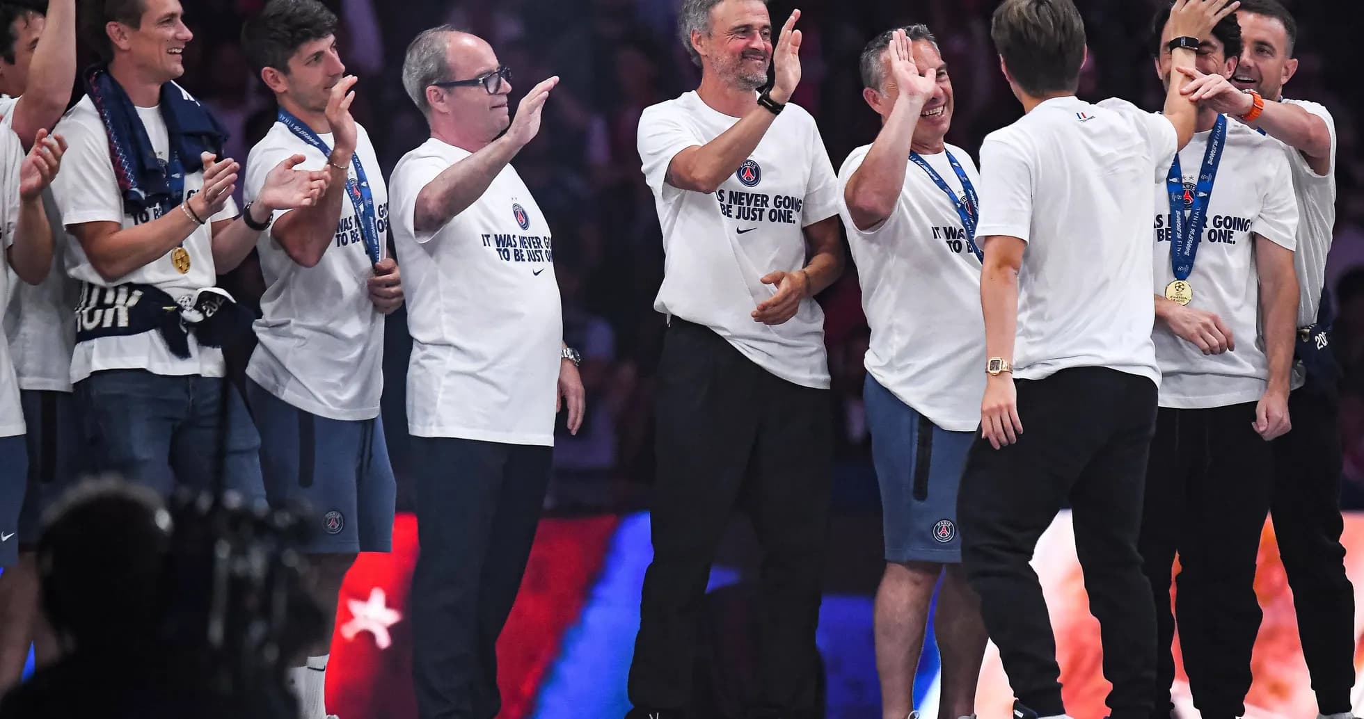 Coaching staff celebrating with team medals on stage Coaching staff celebrating with team medals on stage