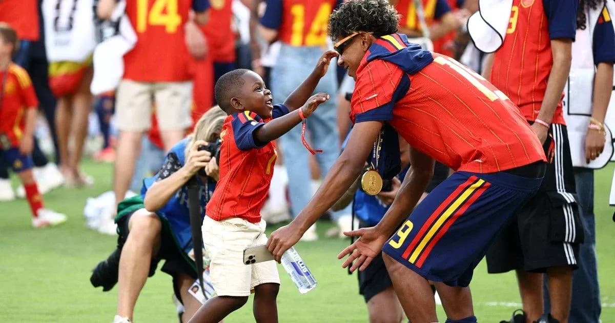 Bola o'ynayotgan bolalar va futbolchi quchoqlashmoqda Bola o'ynayotgan bolalar va futbolchi quchoqlashmoqda