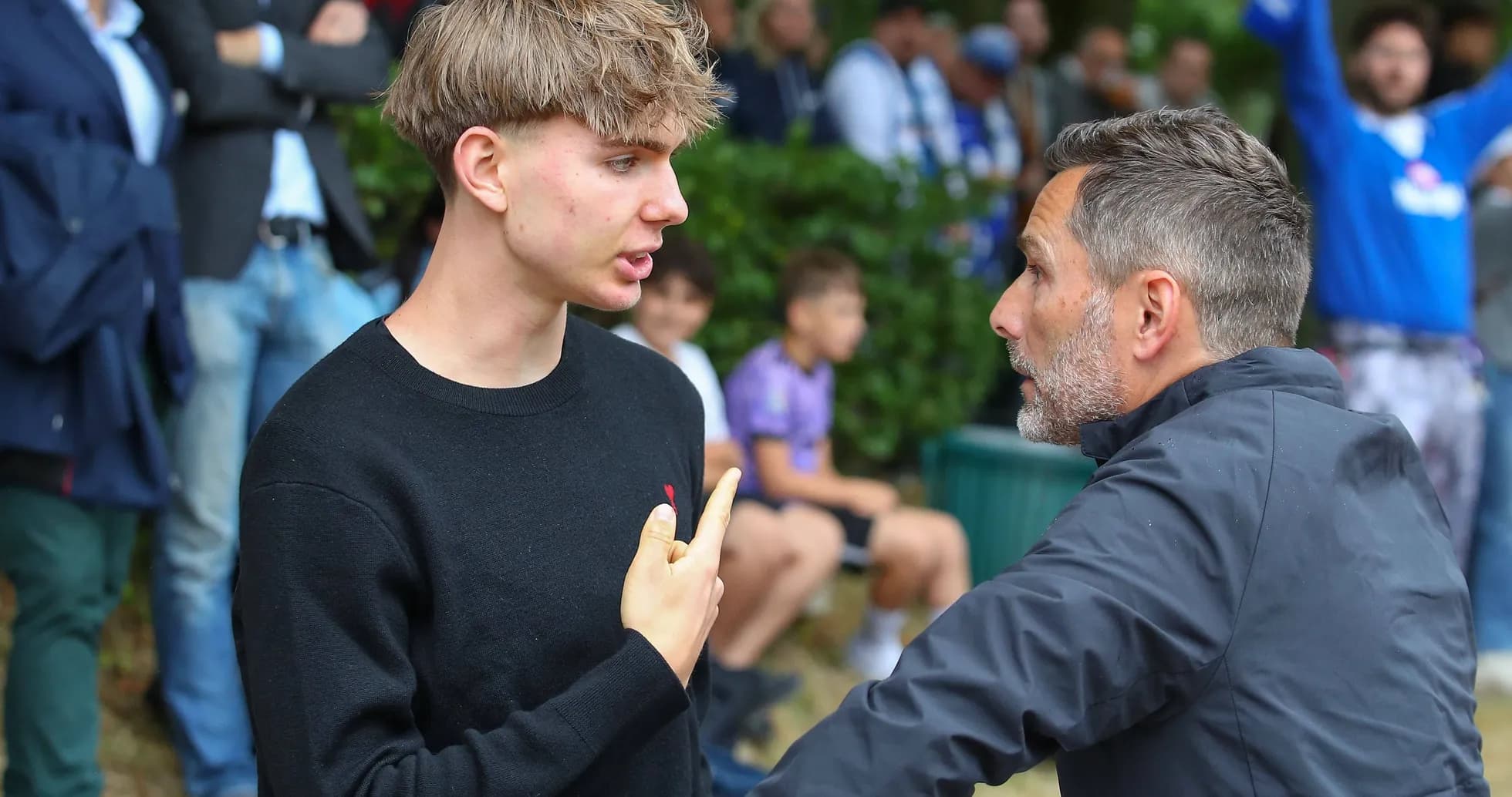 Young man and adult discussing on sidelines Young man and adult discussing on sidelines