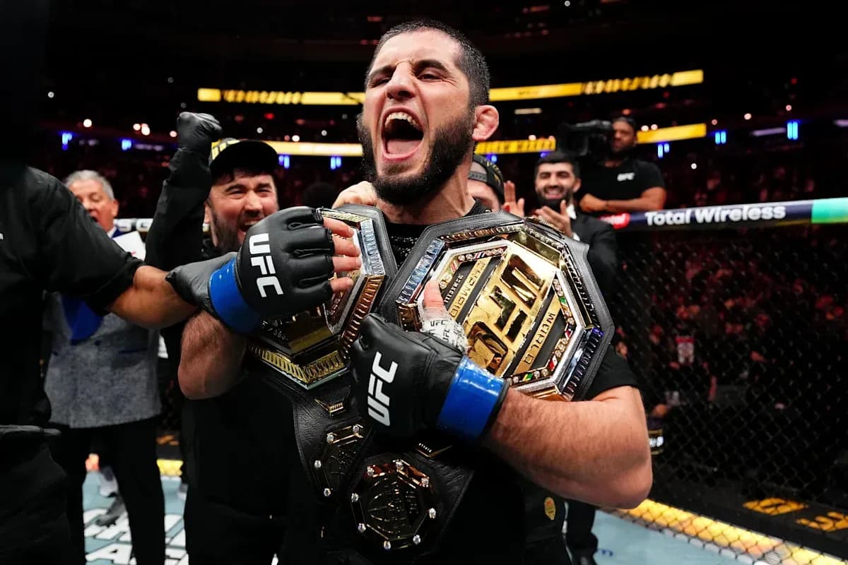 Fighter celebrating with two championship belts in octagon Fighter celebrating with two championship belts in octagon