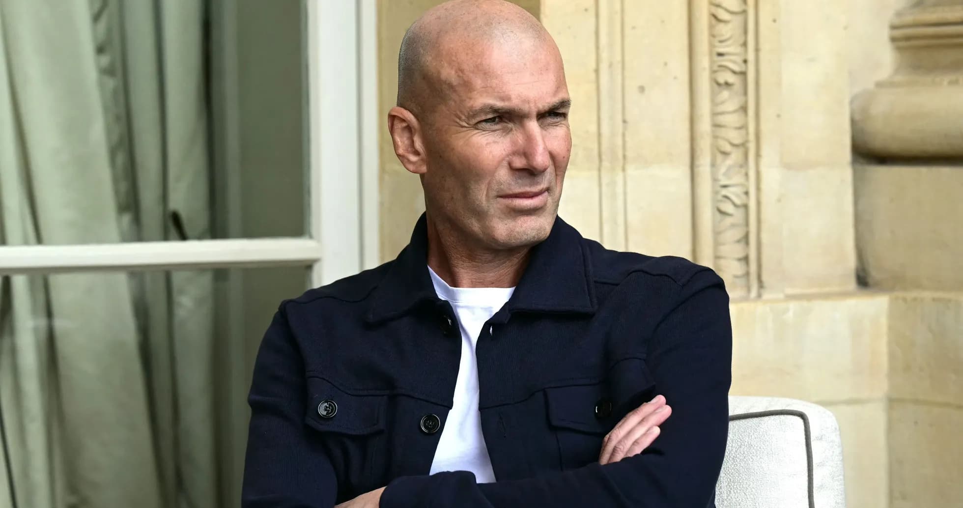 Bald man in navy jacket seated outdoors Bald man in navy jacket seated outdoors