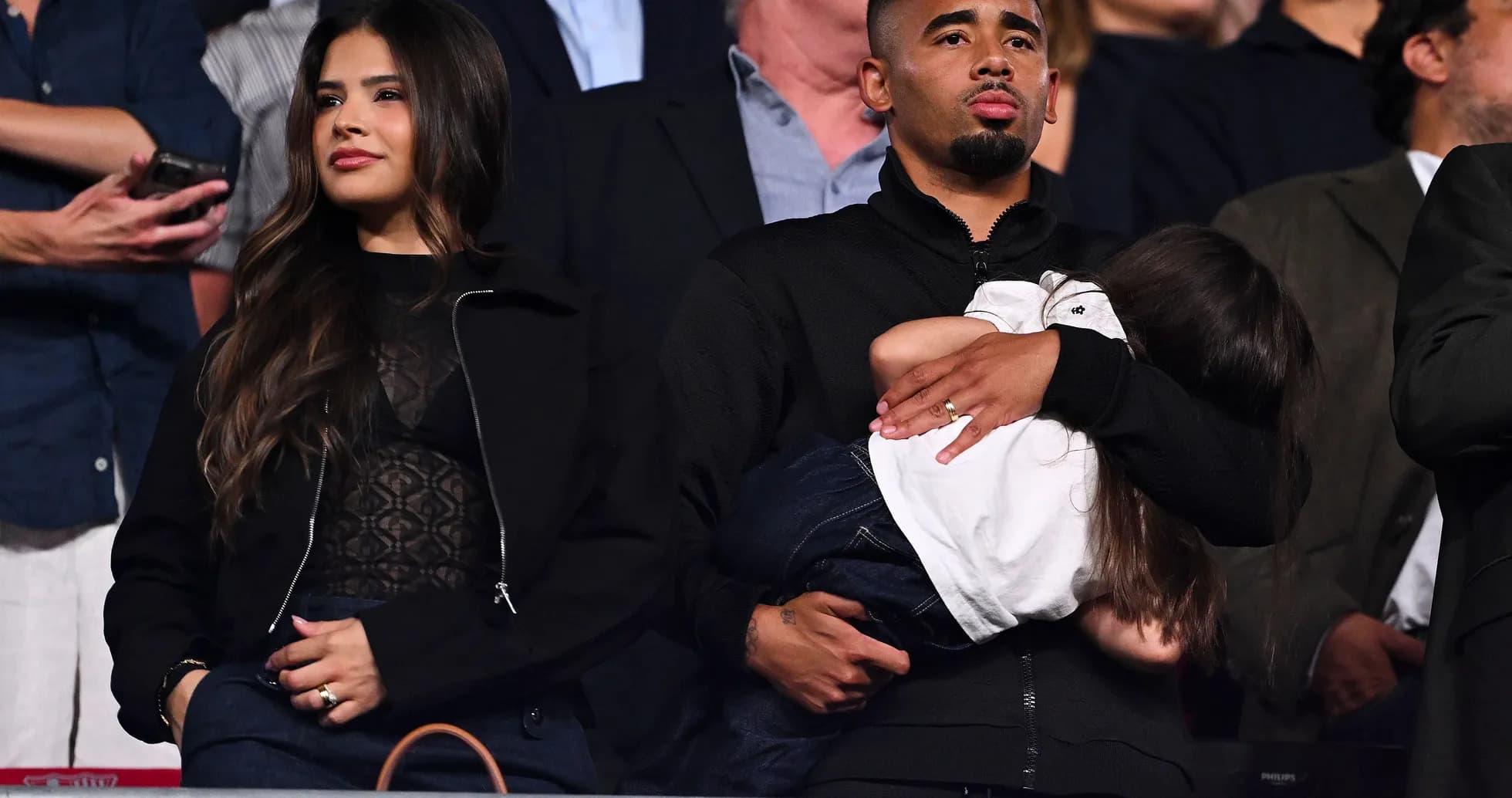 Couple watching event, man holding child Couple watching event, man holding child