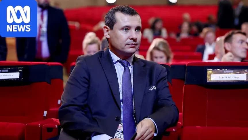 Man seated in conference hall, audience in background Man seated in conference hall, audience in background
