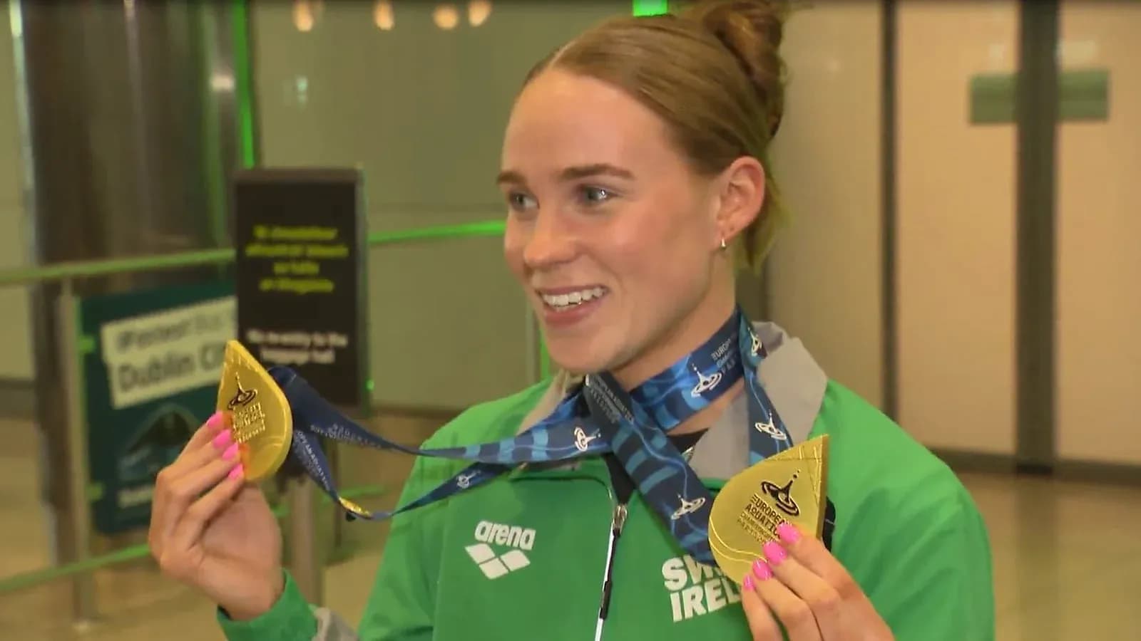 Sportchi oltin medal bilan aeroportda tabassum qilmoqda Sportchi oltin medal bilan aeroportda tabassum qilmoqda