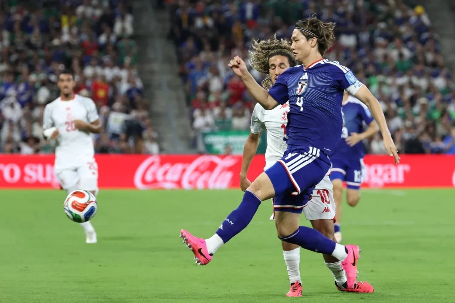 Japanese player kicking ball during match against opponent Japanese player kicking ball during match against opponent