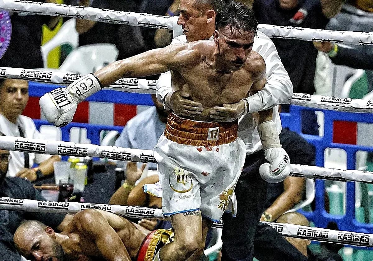 Boxer being helped after a match, opponent on canvas Boxer being helped after a match, opponent on canvas